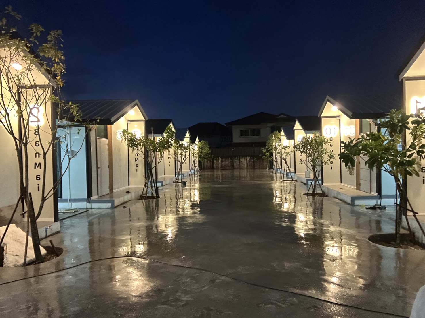 ทางเดินระหว่างบ้านพัก Ban Mai Homestay ยามค่ำ ไฟส่องสว่างสะท้อนพื้น